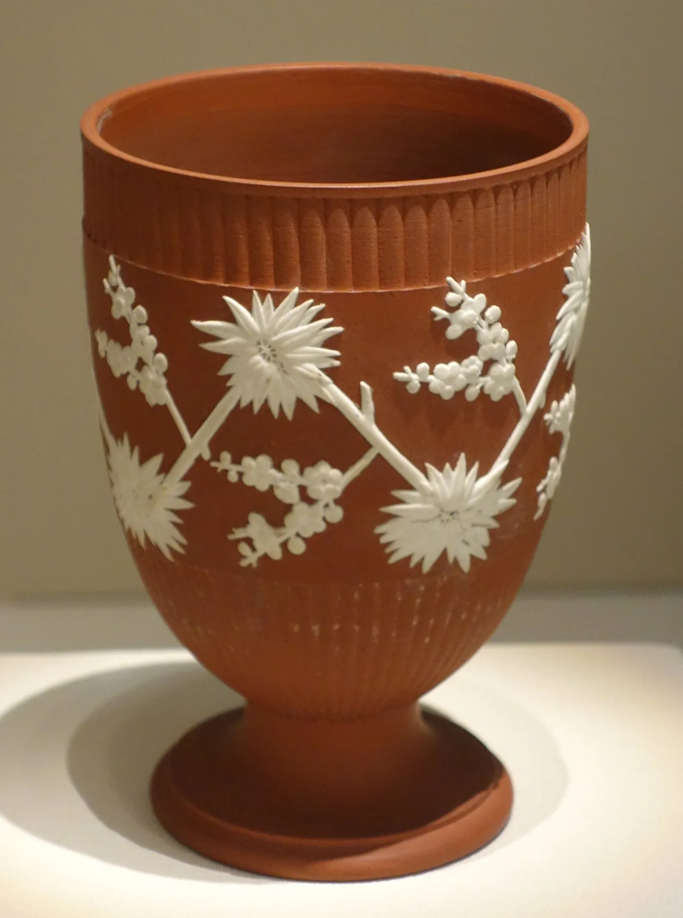 Footed red Wedgwood jasper goblet with white applied flowering branches, the interior of the bowl the same red as the outside