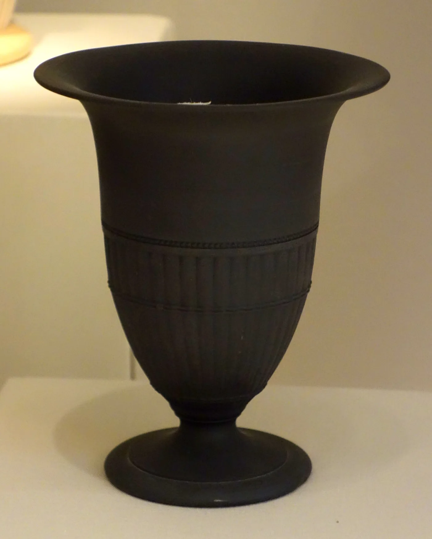 Plain black footed Wedgwood vase with fluted decoration in the same black body, no white ornament